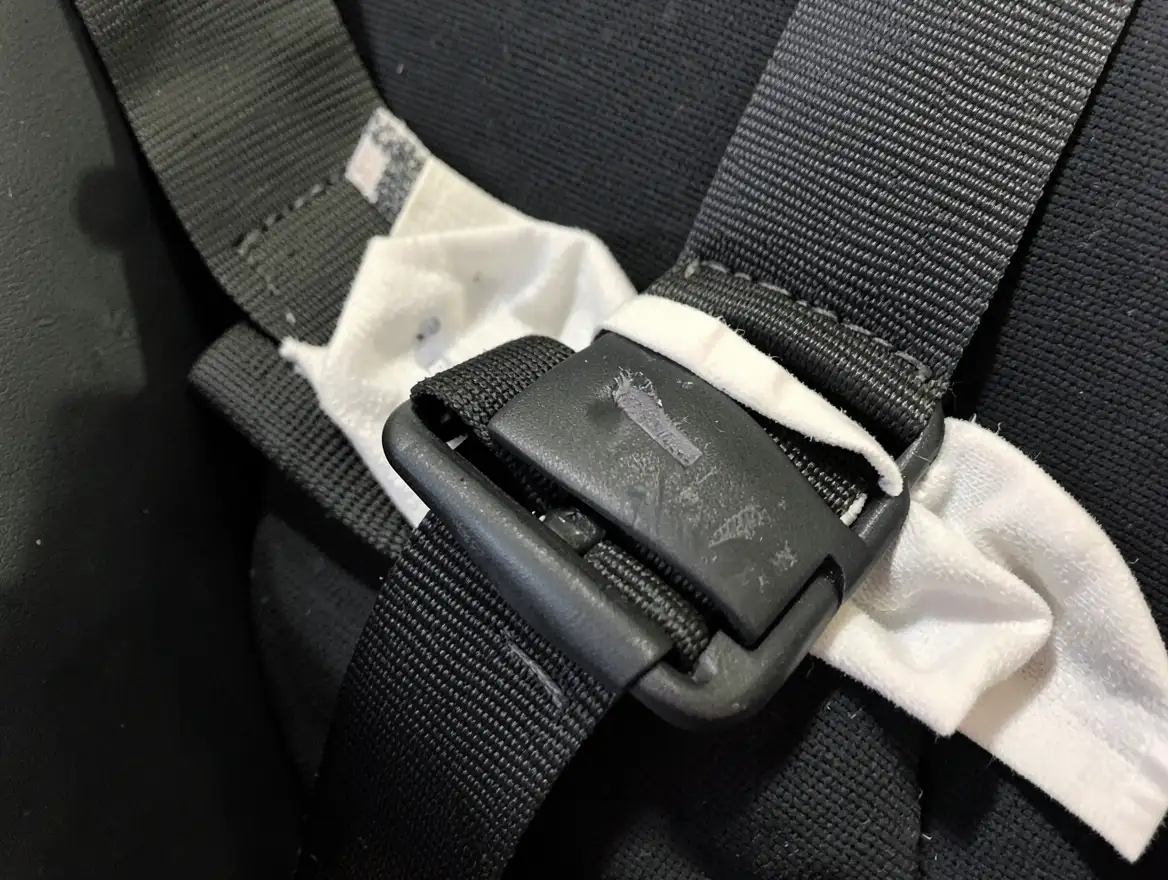 Car seat harness strap and buckle being wiped with a damp cloth instead of machine washing
