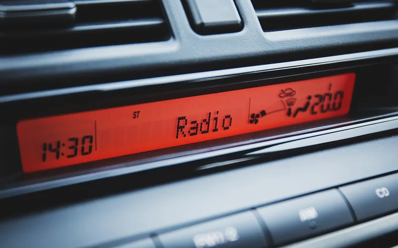 A car stereo display showing the Radio source above the dashboard buttons
