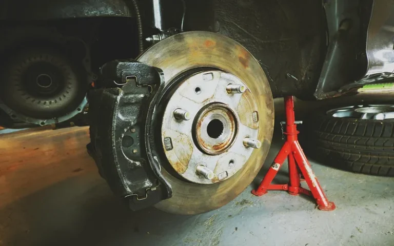 Car wheel hub and brake rotor with the wheel removed beside a jack stand