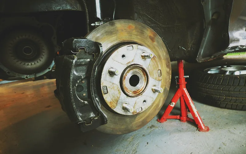 Car wheel hub and brake rotor with the wheel removed beside a jack stand