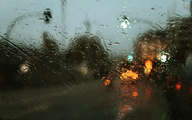 Raindrops beading on a car windshield during heavy rain