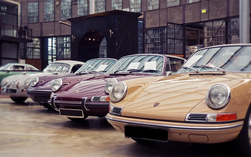 Row of classic cars parked inside a brick-walled showroom