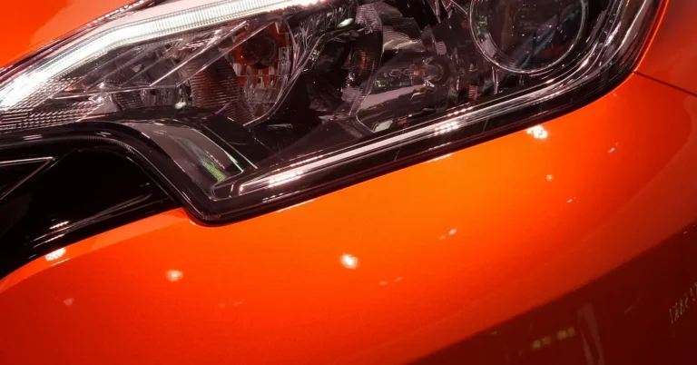 Close-up of a clear plastic car headlight lens on an orange car