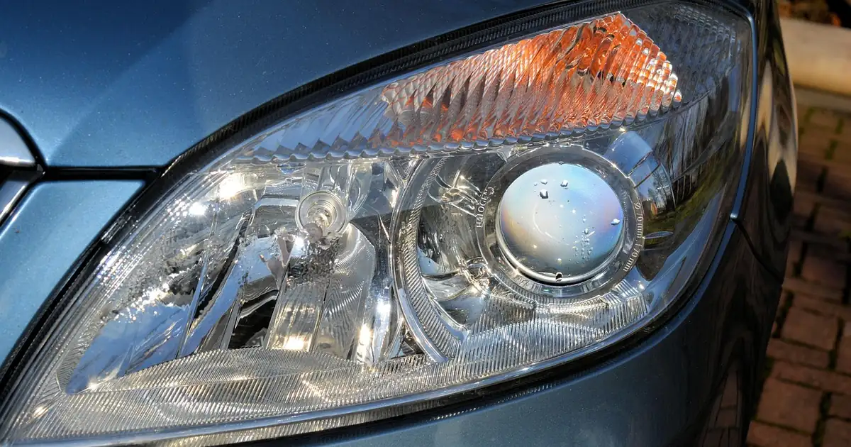 Clear car headlight lens on a blue car body