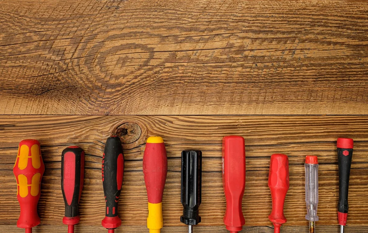 Flathead screwdriver and pliers used to manually release a broken hood latch