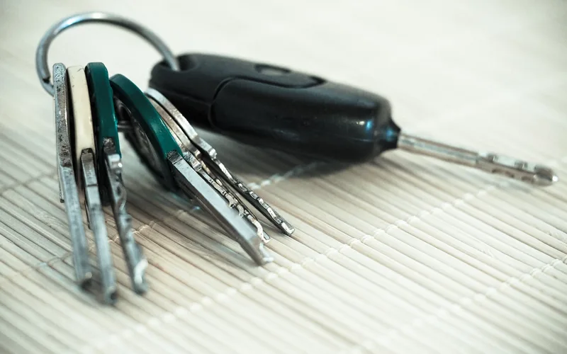 A car key with a remote fob on a ring with several other keys