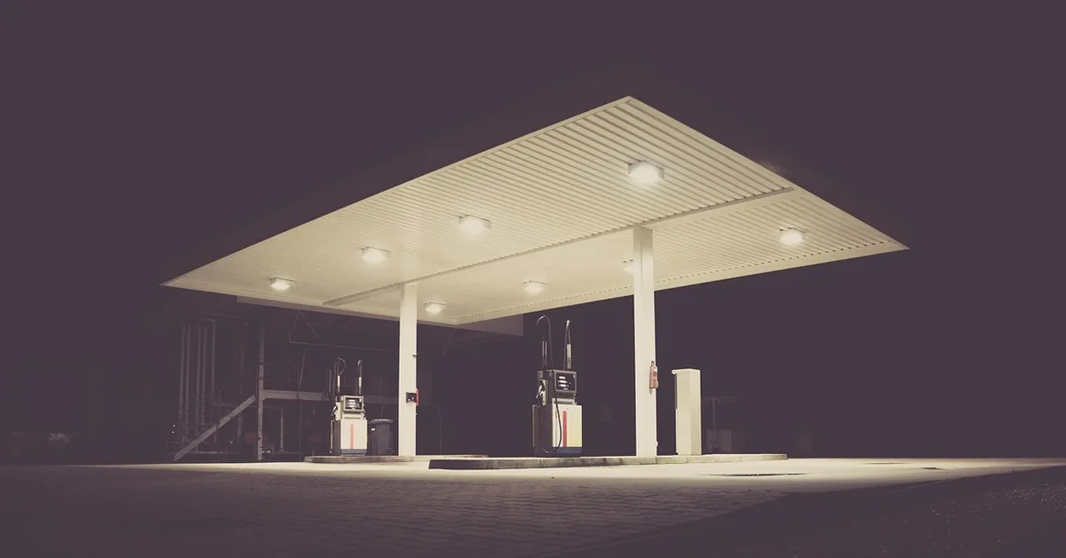 Gas station canopy lit at night with two pumps underneath