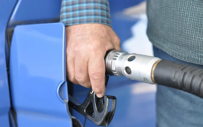 Hand holding a fuel nozzle in a car fuel filler opening Hand holding a fuel nozzle in a car fuel filler opening