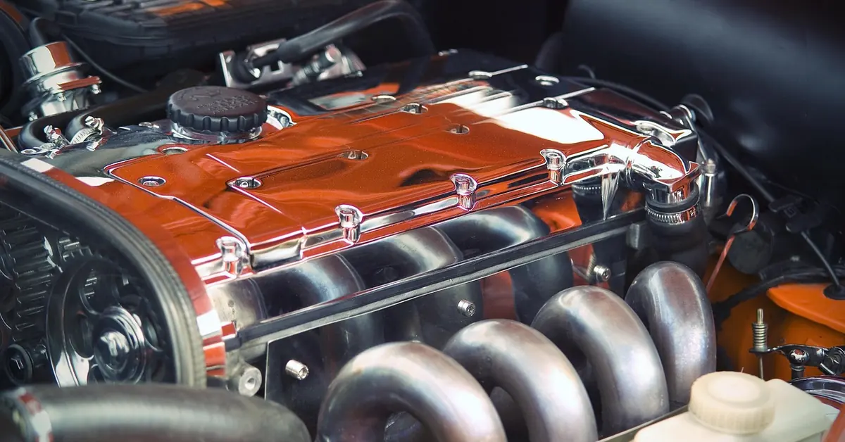 Car engine with a polished cylinder head cover, intake runners and a coolant overflow bottle