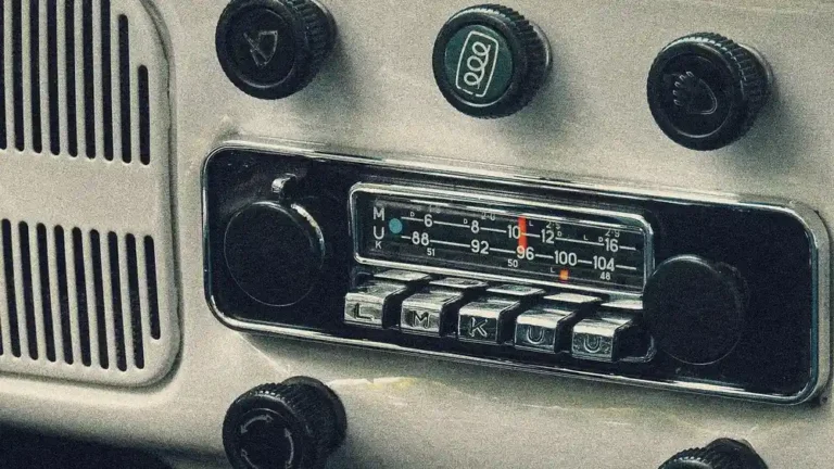Older factory car radio with push buttons and a frequency dial set in a light grey dashboard