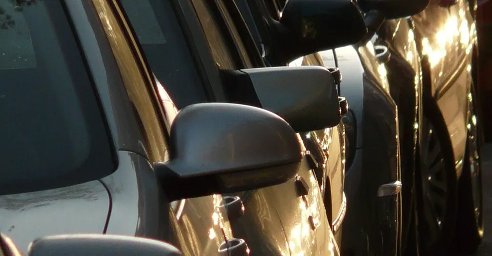 Row of parked cars with side mirrors catching low sunlight