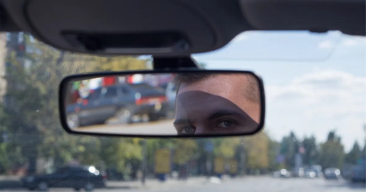 Driver checking the rearview mirror on a city street