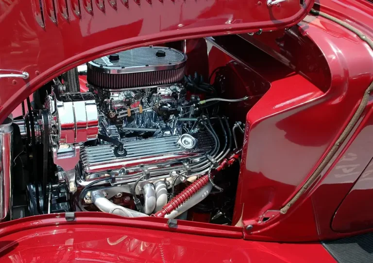 Open hood showing a chrome engine with a round air cleaner in a red car engine bay
