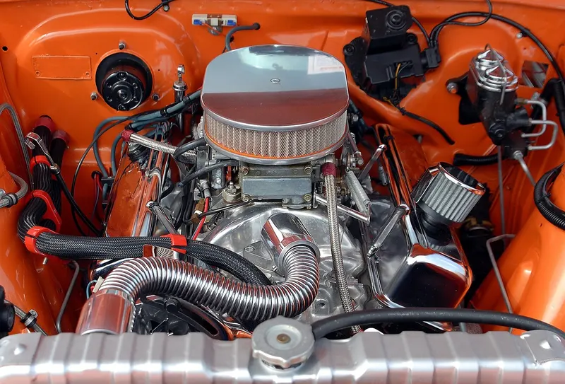 Classic V8 engine bay with a chrome air cleaner and braided hoses