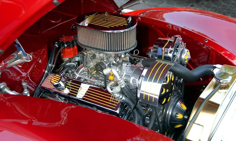Chrome engine with a round air cleaner and valve covers under a raised red hood