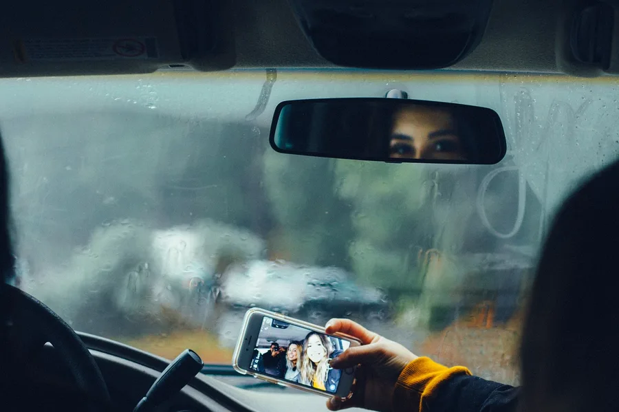 Inside of a car windshield covered in interior fog with finger marks wiped through it