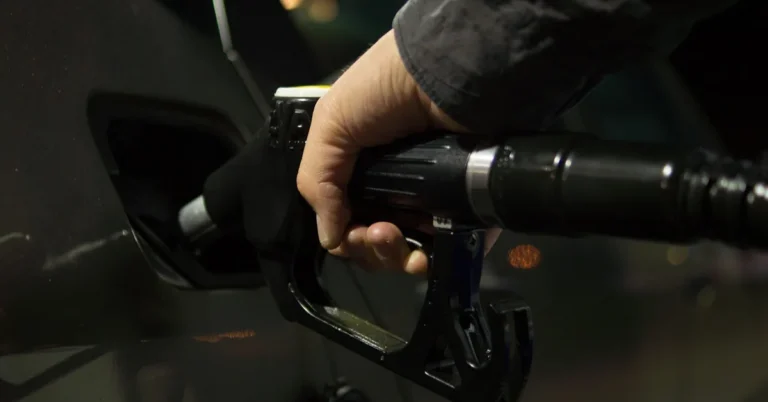 Hand holding a gasoline pump nozzle in a car fuel filler opening
