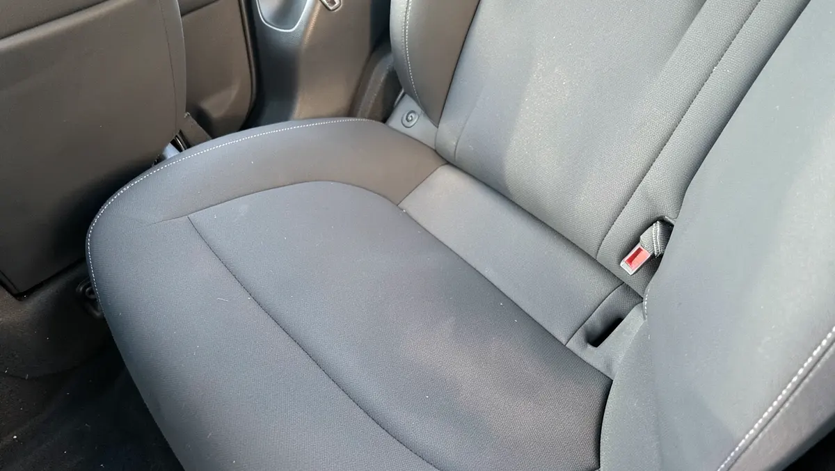 Close-up of a tailored rear bench seat cover showing a contoured seam and seatbelt buckle cutout