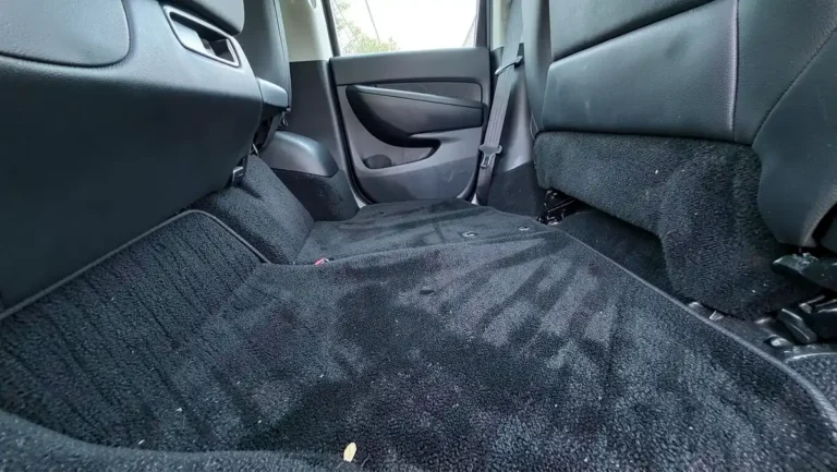 Car back seat footwell showing dark automotive carpet before dyeing