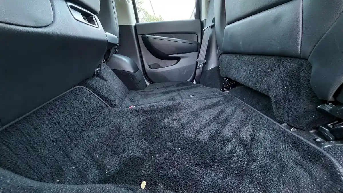 Car back seat footwell showing dark automotive carpet before dyeing