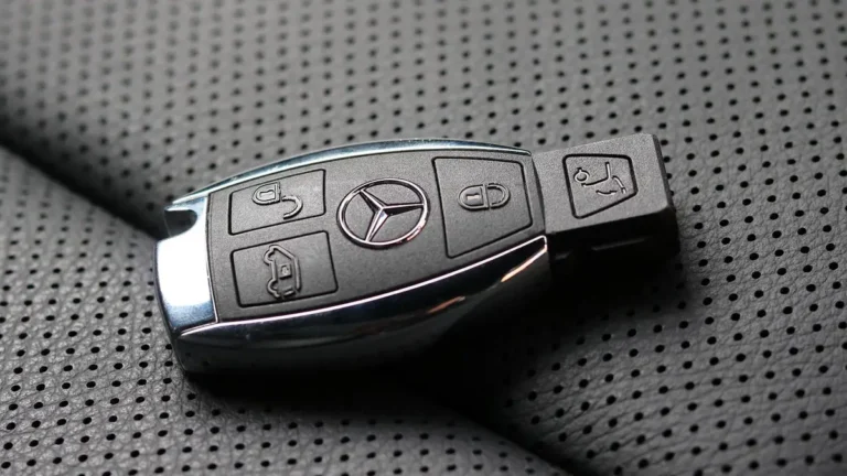 Mercedes SmartKey with chrome edges resting on a perforated leather car seat