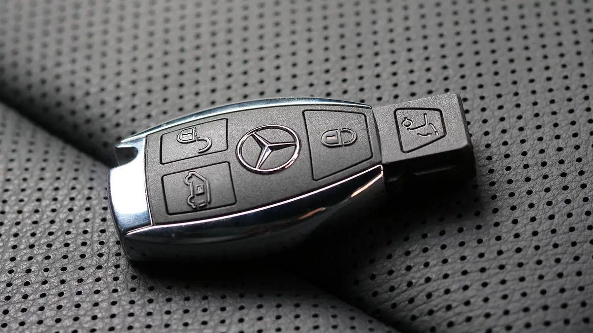 Mercedes SmartKey with chrome edges resting on a perforated leather car seat