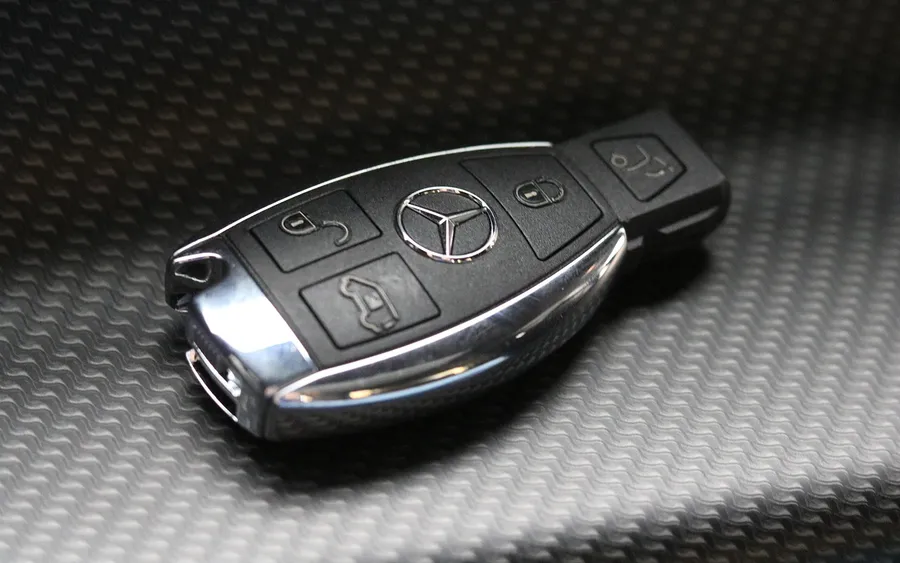 Mercedes SmartKey with chrome edges and mechanical key slot on a carbon-pattern surface