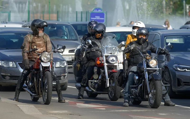 Motorcyclist splitting lanes in city traffic Motorcyclist riding between lanes of city traffic surrounded by cars