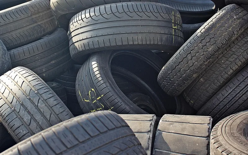 Pile of used car tires with different tread patterns and wear