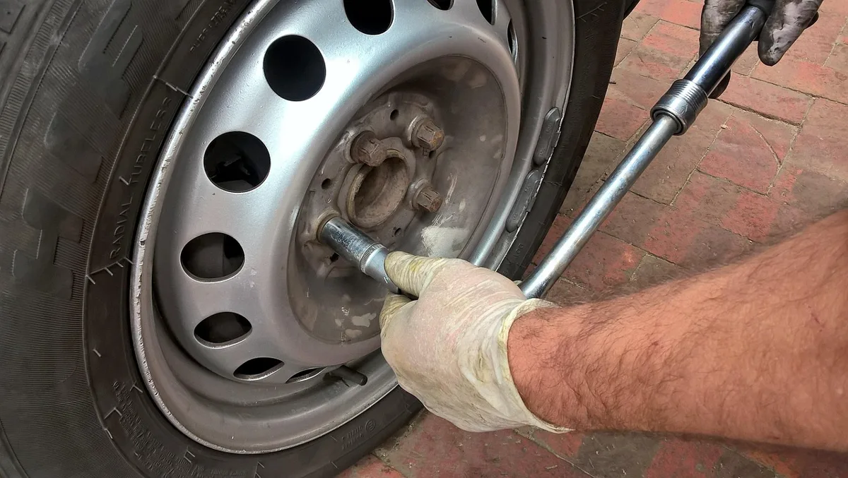 Mechanic rotating a car tire with a lug wrench