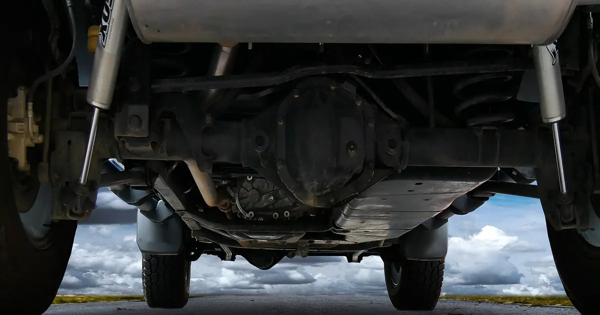 Vehicle underbody with exhaust, axle and frame rails where a tracker could be attached
