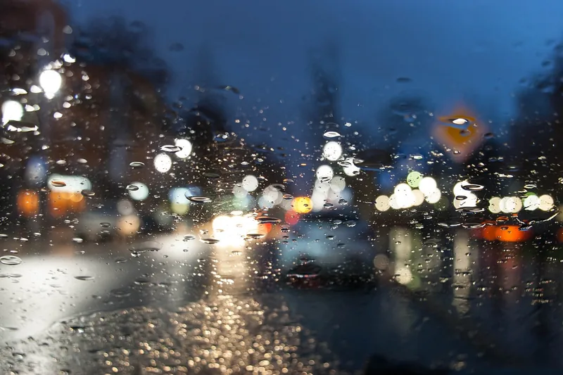 Rain drops on a windshield with blurred evening traffic lights ahead