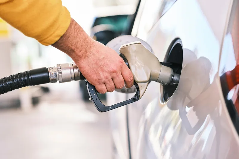 Driver refueling a white car at a gas pump