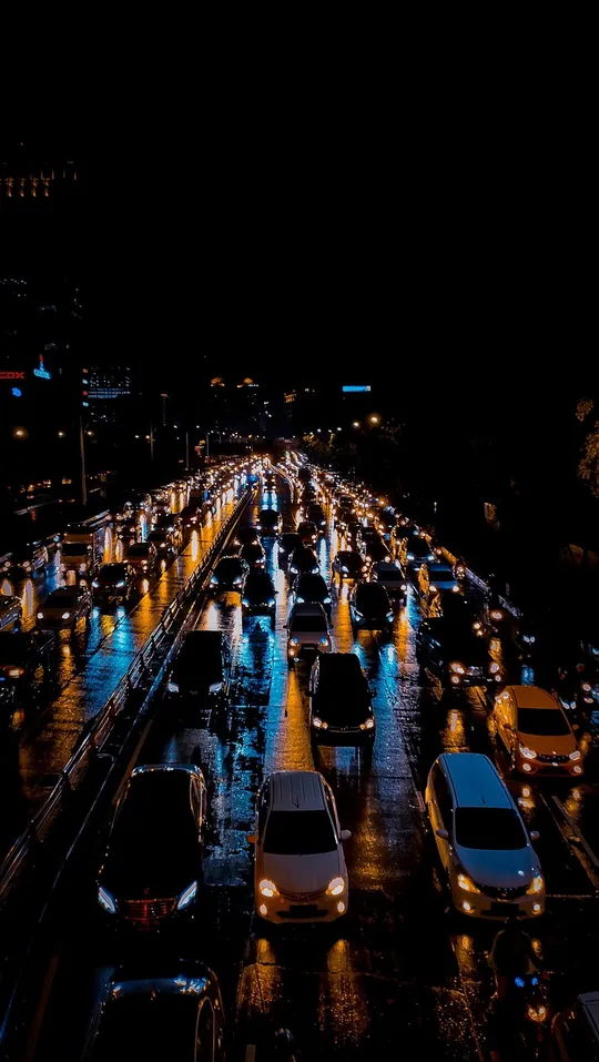Rows of cars in slow evening traffic on a wet road