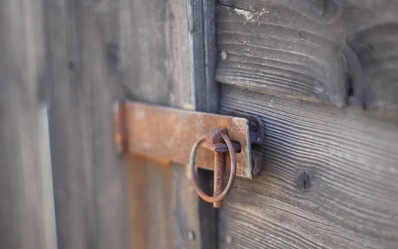 Rusted metal latch with a ring on a weathered wooden door