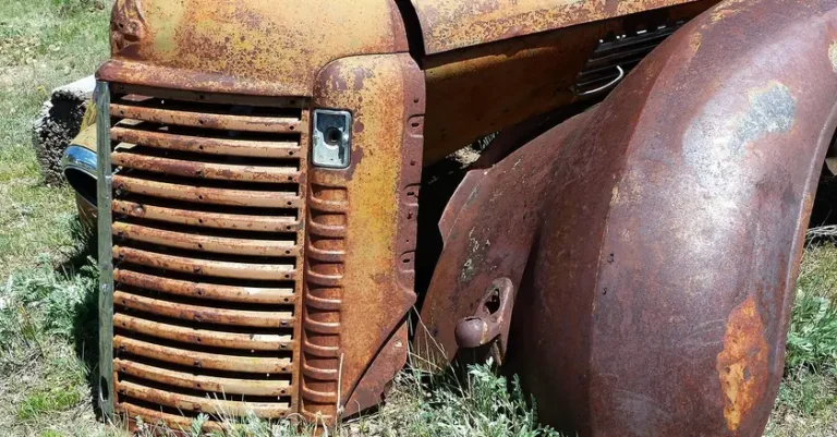Rusty orange and brown fender and hood panel on an old truck