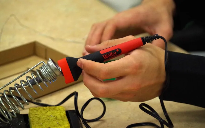 A technician soldering a wire connection during an aux port repair