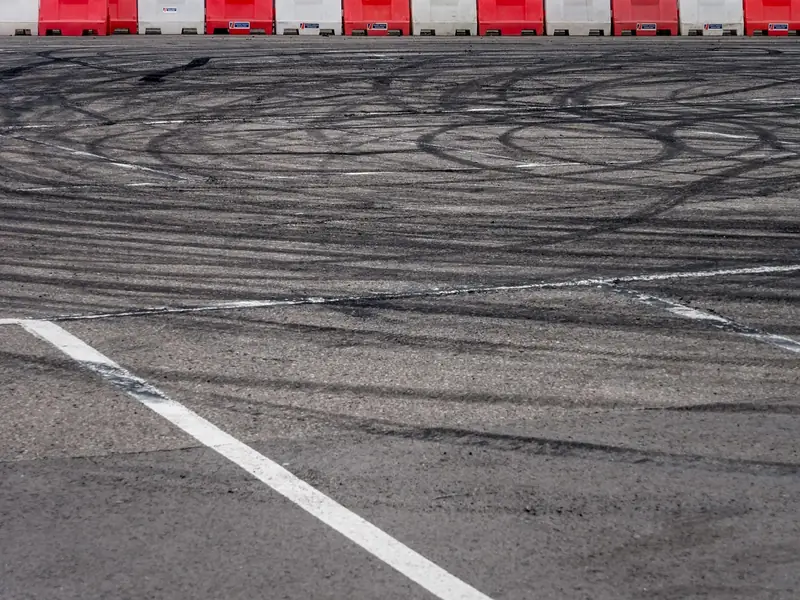 Dark tire marks on a paved surface next to a row of traffic barriers