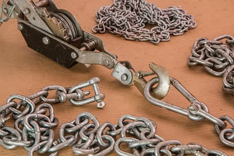 Hand winch with hook and steel chains laid out on a workbench, the kind of recovery gear a tow operator uses