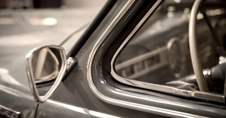 Chrome window trim and side mirror on a vintage car door