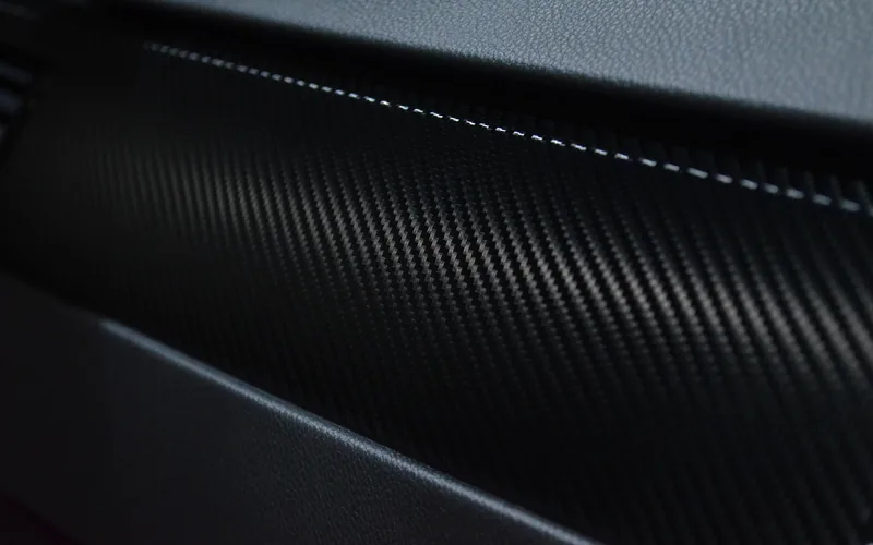 Professional installer applying carbon-fiber vinyl wrap film to a car hood Professional installer applying carbon-fiber vinyl wrap film to a car hood in a wrap shop