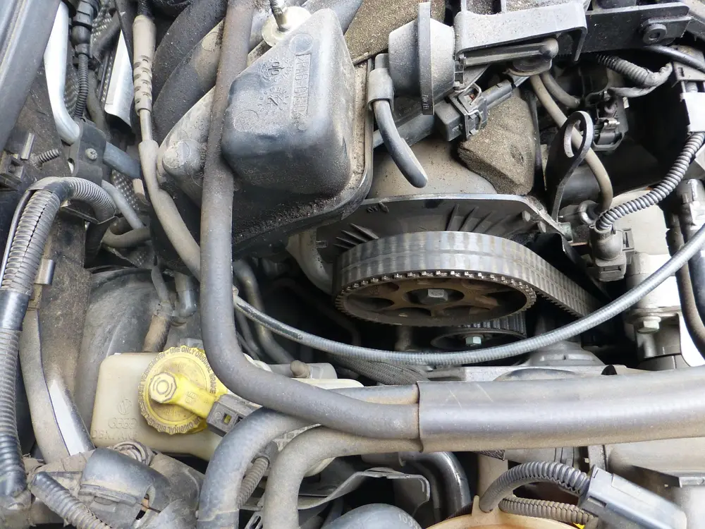 Engine bay of an older car with the timing belt cover removed