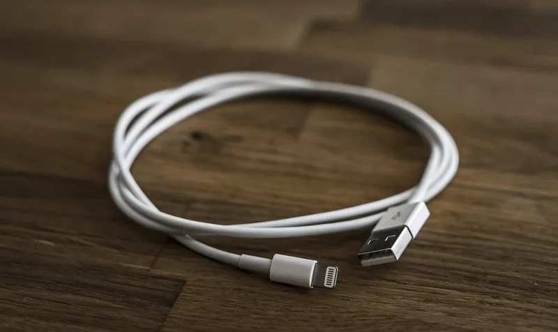 Coiled white USB to Lightning charging cable on a wooden table