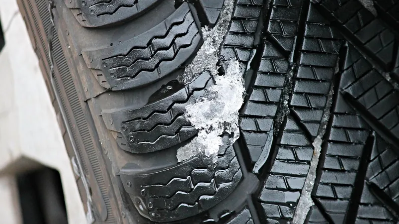 Close view of a winter tire tread with snow packed in the grooves Close view of a winter tire tread with snow packed in the grooves