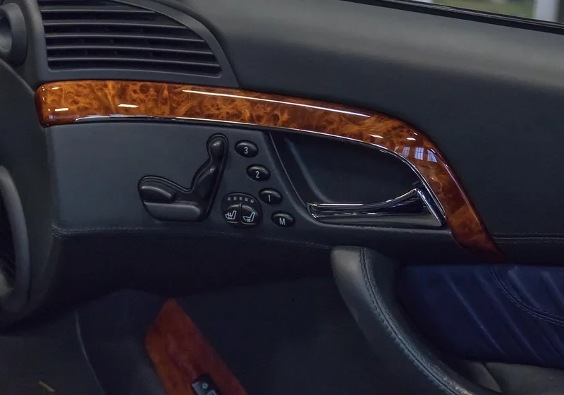 Wood-grain trim strip above an interior door handle and seat controls
