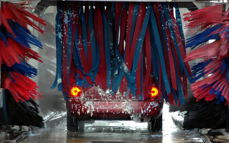 Automatic car wash spraying water and soap onto a vehicle through soft brushes