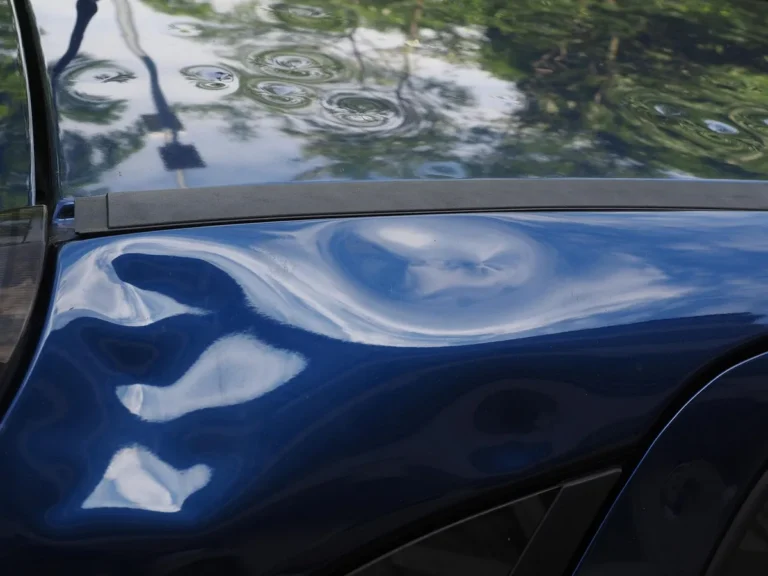 Dent in a blue car panel distorting the reflections