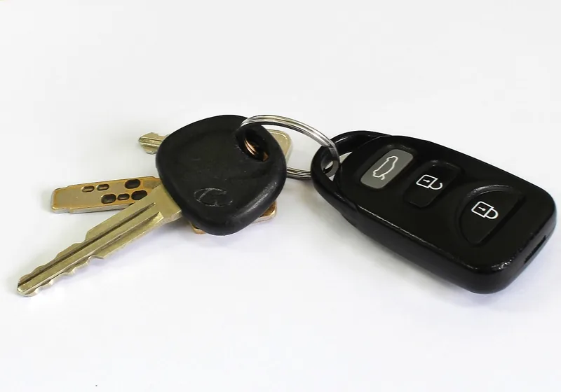 Car key with a thick plastic head next to a remote fob on a key ring