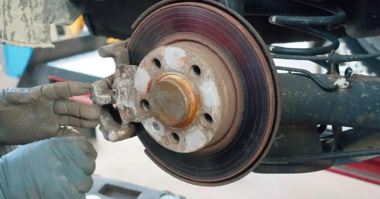 Rear suspension of a car on a lift with a coil spring, axle beam and brake disc visible