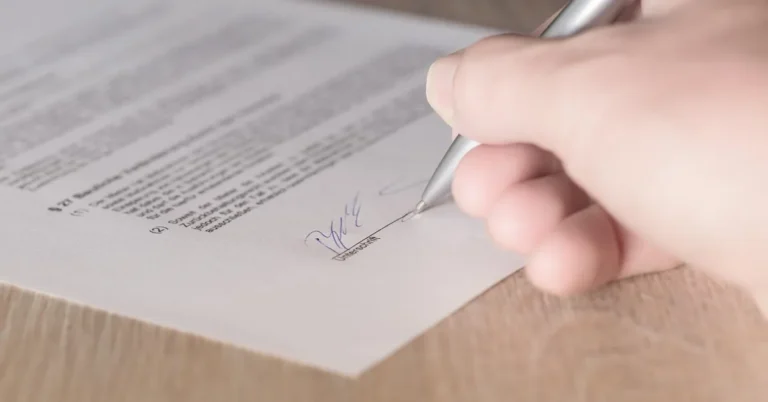 Hand signing a printed contract with a pen
